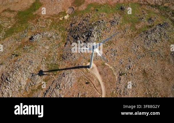 Drone view directly above a wind turbine standing on rugged rocky ...