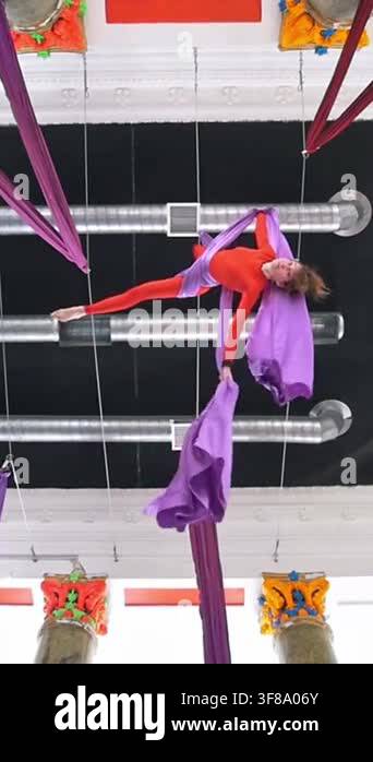 Attractive girl air gymnast flying upside down on the aerial silk ...