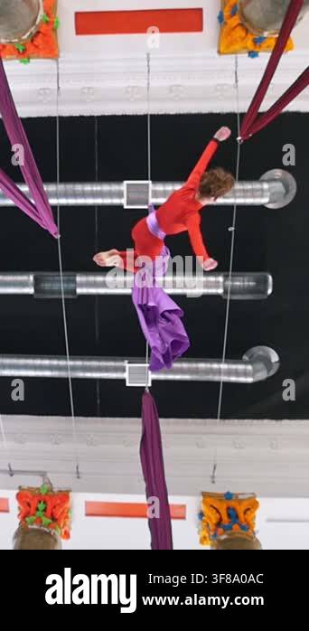 Beautiful woman air gymnast hangs upside down on the aerial silk ...