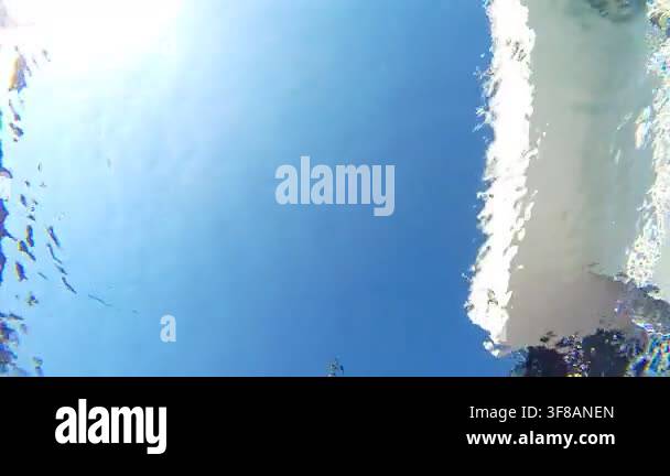 View from bottom of pool to young man jumping into crystal clear water ...