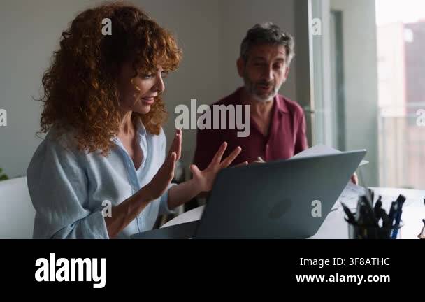 Two focused middle aged professionals discussing a project in an office ...