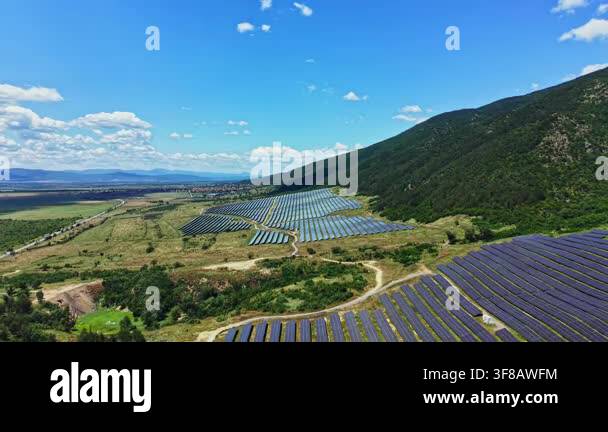 Solar panels are arranged in rows on the hillside. The landscape ...