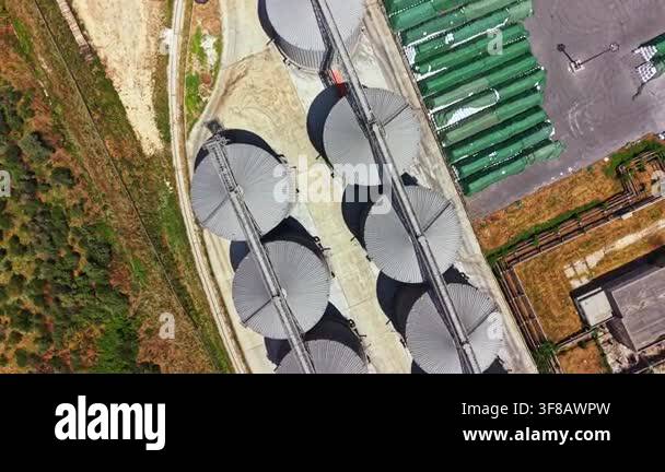 Aerial view shows large storage silos arranged in rows next to green ...