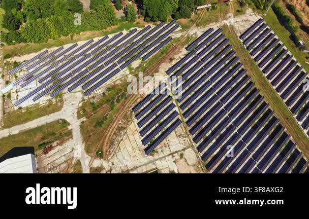 Solar panels are arranged neatly in rows at a site during the daytime ...