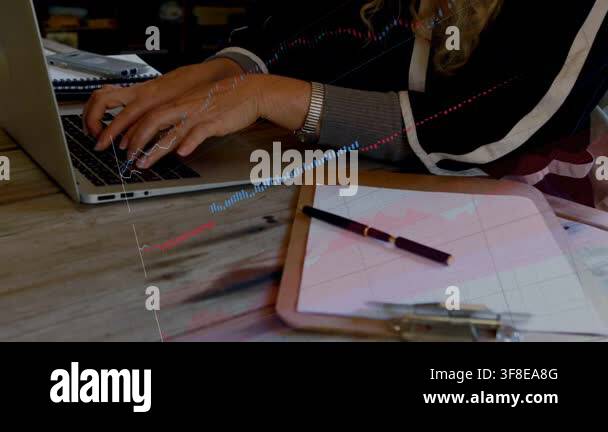 Woman typing on laptop at desk, starting finance charts sweeping across ...