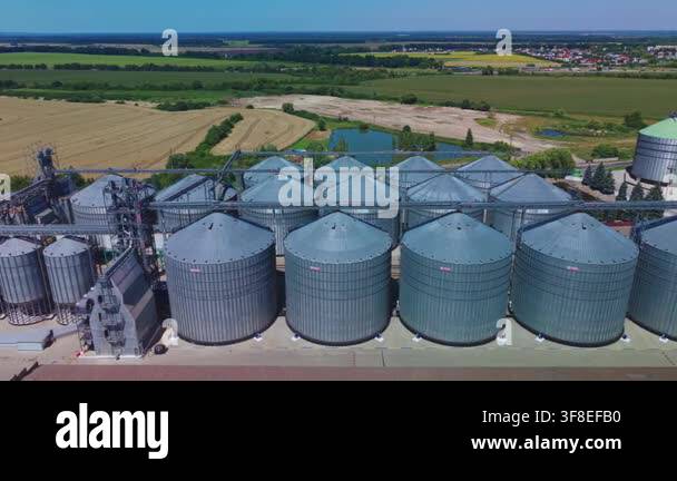 Dynamic aerial view captures rows of silver steel grain silos at modern ...