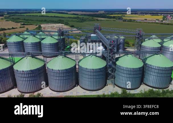 Dynamic aerial overview reveals large silver metal grain silos with ...