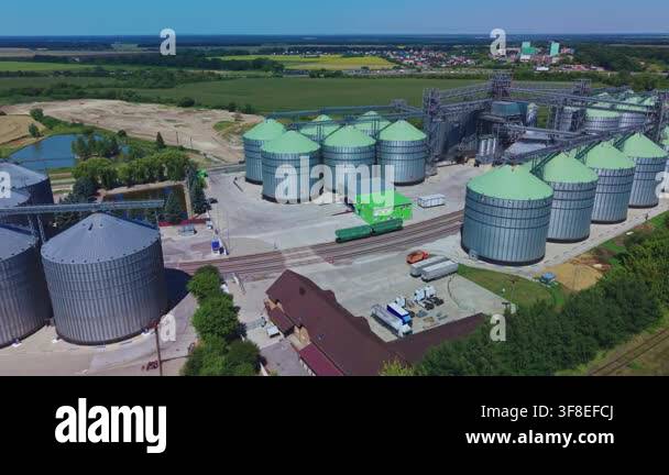 Dynamic aerial overview reveals rows of silver and green metal silos ...