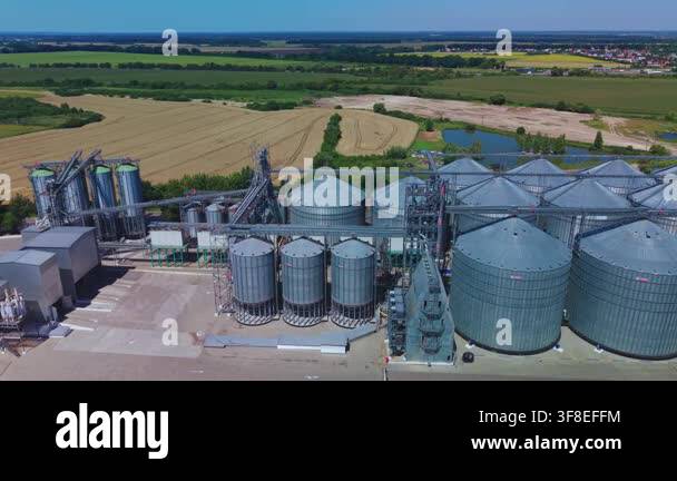 Dynamic aerial overview reveals large silver metal silos of modern ...