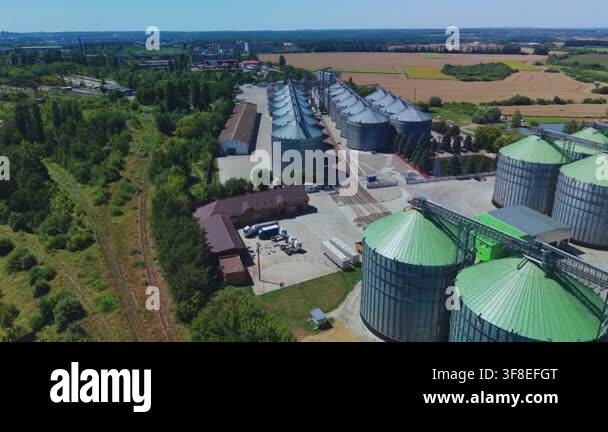Dynamic aerial overview reveals industrial steel silos of modern grain ...