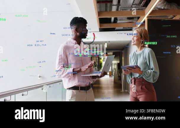 Discussing pair using laptop tablet in office hallway by glass railing ...