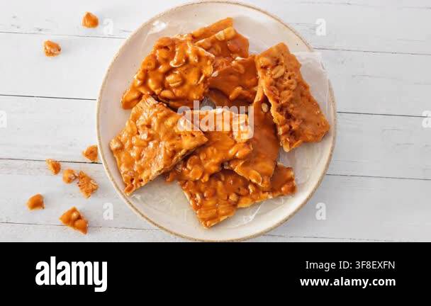 Plate of traditional peanut brittle candy pieces. Top view on a white ...