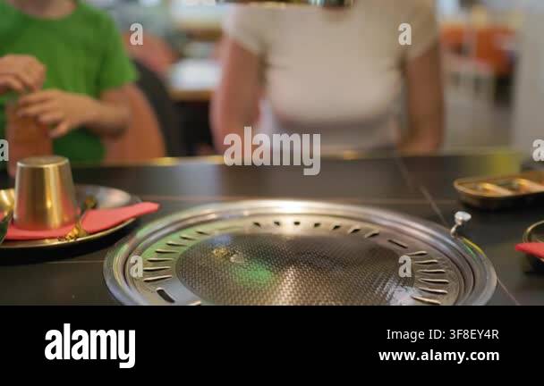 Waiters hand adjusting the exhaust hood over a built-in table grill in ...