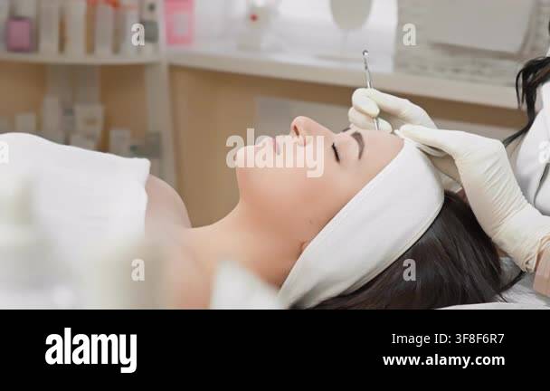 Aesthetician applies advanced facial therapy to a female client in a ...