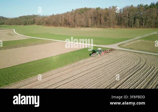 Aerial view of moving tractor plows the land in spring. Heavy machinery ...