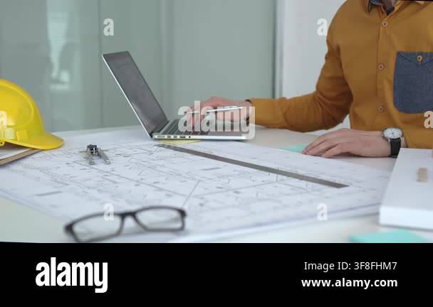 Architect working on construction plans using a laptop, drafting new ...