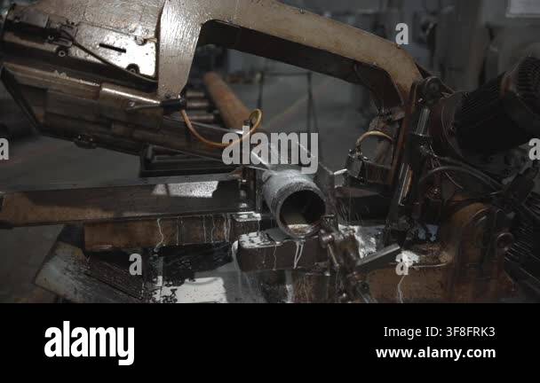 Close view of industrial bandsaw blade cutting cylindrical steel pipe ...