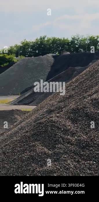 Steep slope of rough grey gravel mound on industrial construction site ...