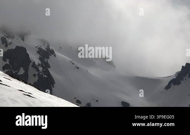 Time lapse view shows a snowy mountain pass under winter clouds in ...