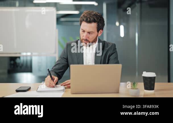 Focused individual diligently writing notes at modern office desk ...