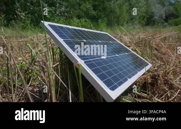 A small photovoltaic solar panel is positioned at an angle on a dry ...
