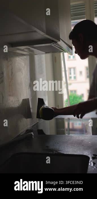 Vertical video showing person cleaning kitchen wall with steam cleaner ...