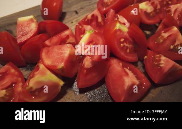 Fresh tomatoes cut into pieces and arranged on a dark wooden cutting ...