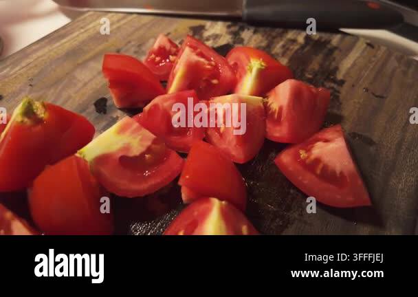 Fresh tomatoes cut into pieces and arranged on a dark wooden cutting ...