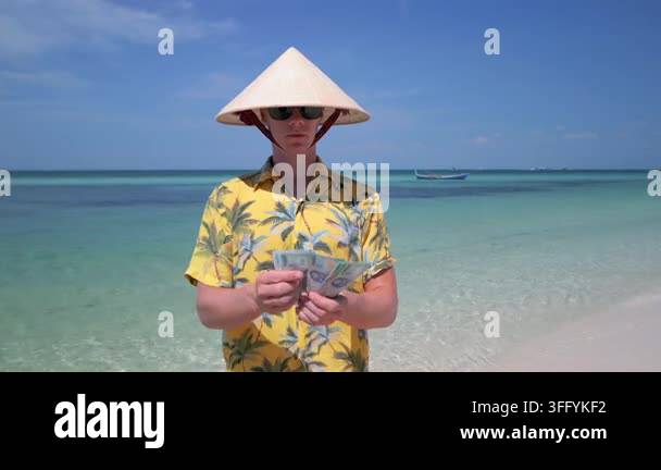 Close-up of man counting Vietnamese dong banknotes on a tropical beach ...