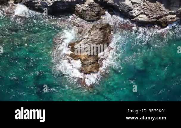 Aerial view of rocky coastline with waves crashing against the shore ...