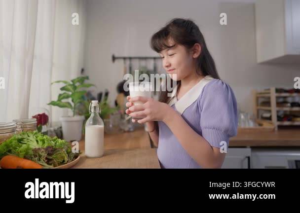 Young Girl Holding A Glass Of Milk While Standing In A Bright Kitchen Young Girl Holding A Glass Of Milk While Standing In A Bright Kitchen