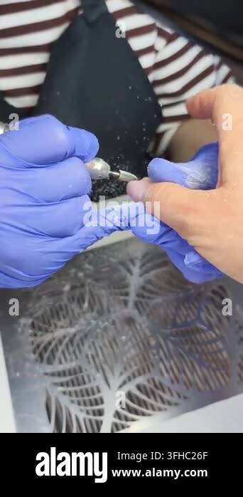 An electric manicure procedure at a beauty salon. A technician wearing ...