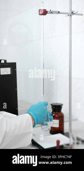 Laboratory technician works with a graduated glass burette and beaker ...