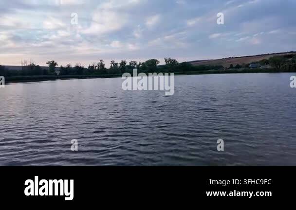 Serene lake at sunset with gentle waves and dramatic clouds overhead ...