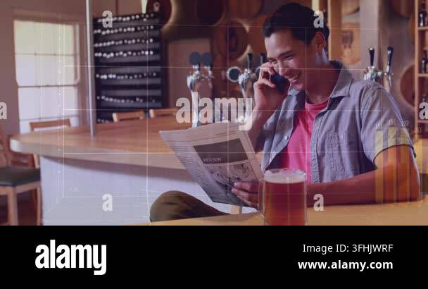Glanicing Man at bar glancing then lifting phone, sharing article while charts ...