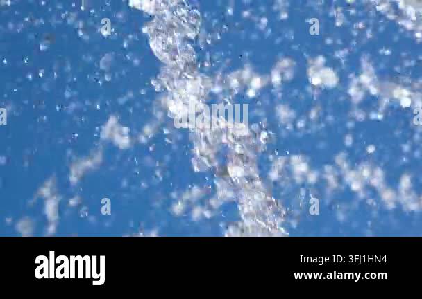 Close-up of sparkling fountain water splashes against clear blue sky ...