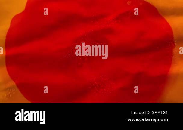 Abstract close up of red liquid flowing over a textured yellow surface ...