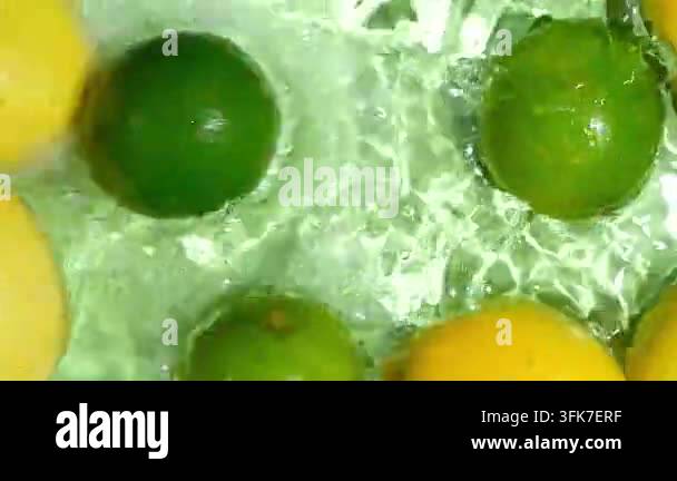 Whole limes falling into water with lemons slow motion splash top view ...