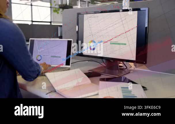 Data analyst placing pages at desk, comparing screen graphs with ...