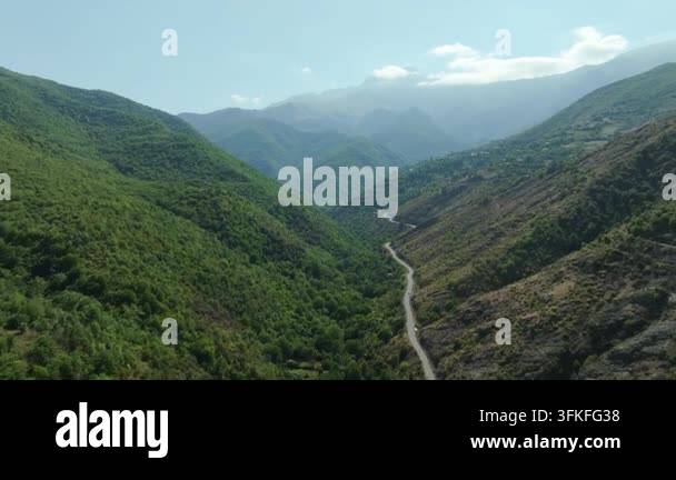 Aerial view of a winding road through a lush green mountain valley ...