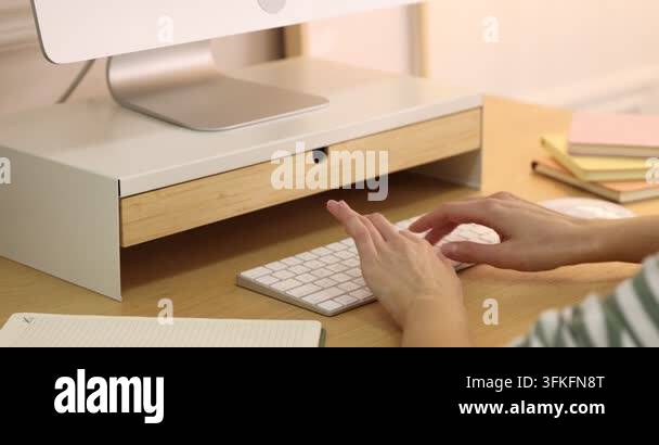 Computer Sdreem Riser Woman taking glasses out of under monitor riser at wooden desk indoors ...