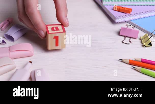 Woman putting cubes with letters and numbers on white wooden table ...