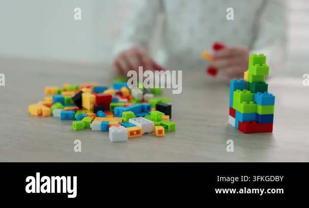 Little girl playing with colorful building blocks at wooden table ...