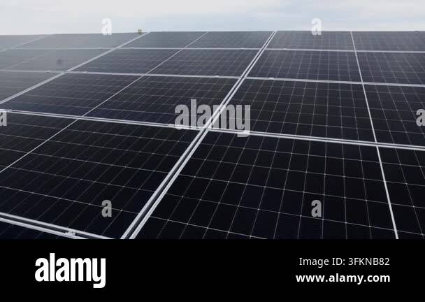Close-up aerial view of a large solar panel array under a cloudy sky ...