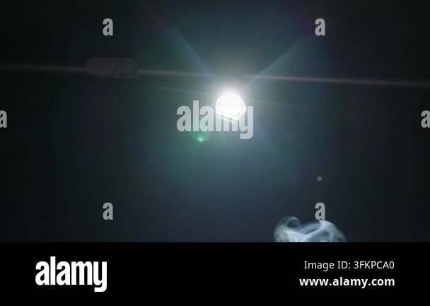 An intense light beam shines from a flashlight through floating smoke ...
