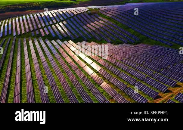Drone view of solar panel rows on green hillside. Curved panel arrays ...