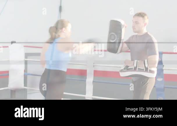 Woman boxer following coach shifting mitts and calling combos in ring ...