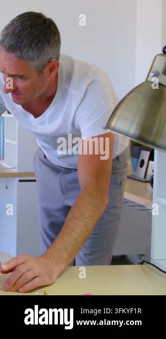 Vertical video: Man leaning over desk in home inspecting screen as data ...