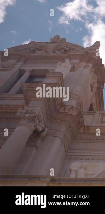 Vertical upward view reveals ornate classical building facade with tall ...