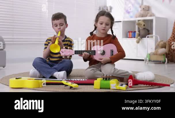 Three Muscal Instruments Cute little kids playing toy musical instruments on floor indoors Stock ...